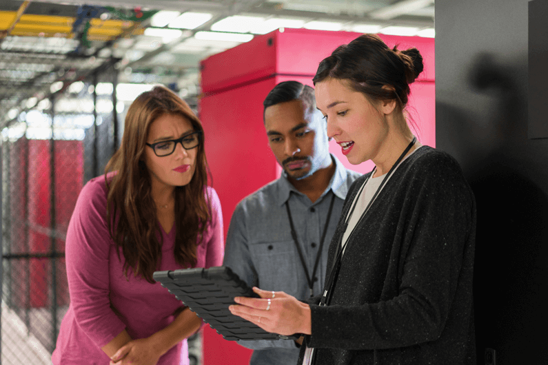 IT professionals review data on a tablet inside a data center, discussing cybersecurity best practices for business.