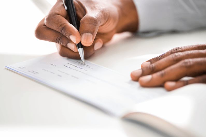image of a person's hands as they write a check